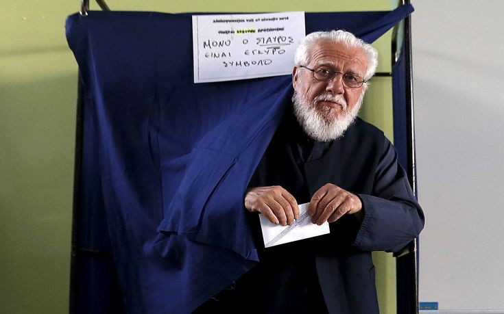 Greek Orthodox priest exits a booth at a polling station  in Athens
