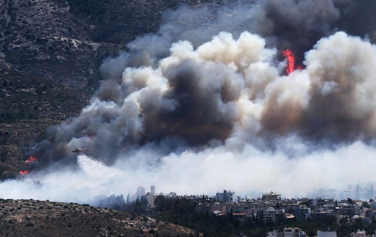 A firefighting helicopter drops water on a raging wildfire at the Kareas suburb, east of Athens, Greece July 17, 2015. Dozens of Athens residents fled their homes on Friday as wildfires fanned by strong winds and high temperatures burned through woodland around the Greek capital, sending clouds of smoke billowing over the city.  REUTERS/Alkis Konstantinidis      TPX IMAGES OF THE DAY