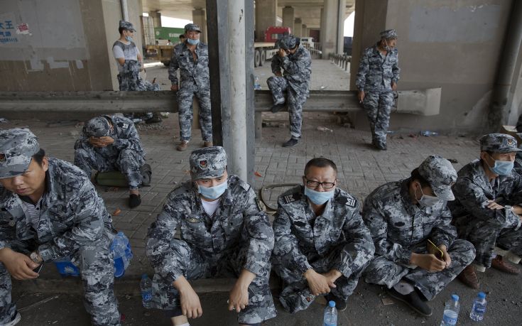 Soldiers rest under the bridge near the explosion site takes pictures of pluming smoke in Binhai new district in Tianjin, China August 13, 2015.Two huge explosions tore through an industrial area where toxic chemicals and gas were stored in the northeast Chinese port city of Tianjin, killing at least 44 people, including at least a dozen fire fighters, officials and state media said on Thursday. REUTERS/Damir Sagolj