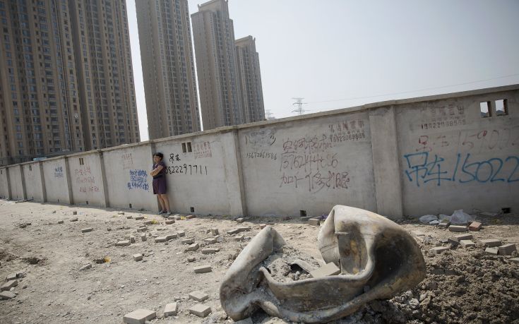 A woman evacuated from a residential area looks at a large metal object that landed and damaged the road about two kilometres from the explosion site in Binhai new district in Tianjin, China August 13, 2015. Two huge explosions tore through an industrial area where toxic chemicals and gas were stored in the northeast Chinese port city of Tianjin, killing at least 44 people, including at least a dozen fire fighters, officials and state media said on Thursday. REUTERS/Damir Sagolj
