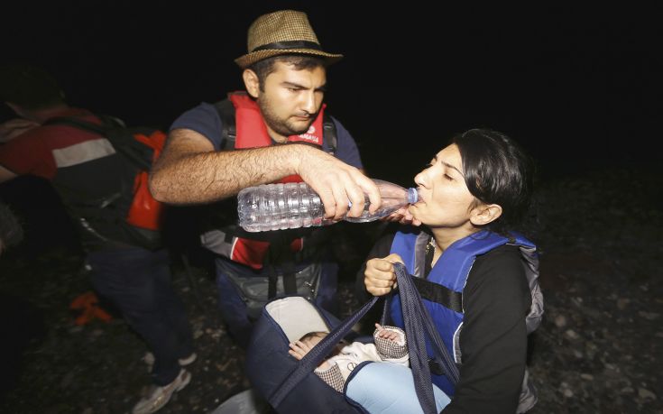 A Syrian refugee gives his wife water moments after arriving at a beach on the Greek island of Kos after crossing a part of the Aegean sea from Turkey to Greece on a dinghy August 13, 2015. The United Nations refugee agency (UNHCR) called on Greece to take control of the "total chaos" on Mediterranean islands, where thousands of migrants have landed. About 124,000 have arrived this year by sea, many via Turkey, according to Vincent Cochetel, UNHCR director for Europe. REUTERS/Yannis Behrakis