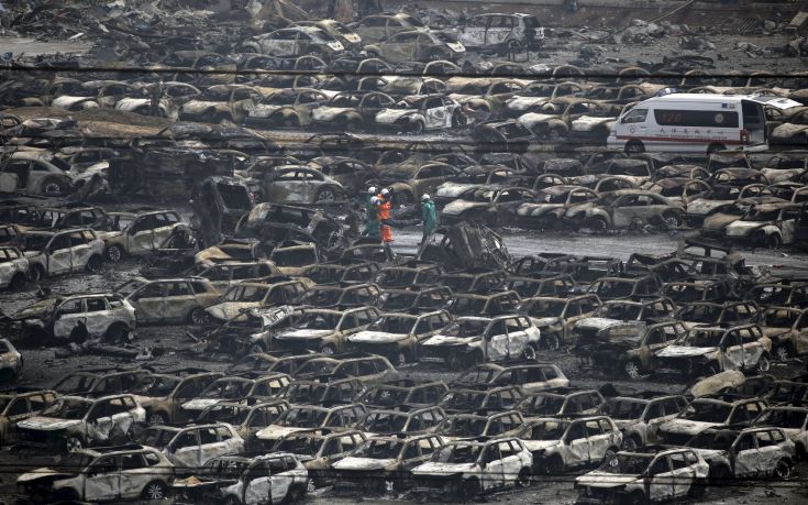Firefighters walk among damaged cars as they carry out the body of a victim from the site of the explosions towards an ambulance at the Binhai new district, Tianjin, China, August 14, 2015. Several Japanese automakers including Toyota Motor Corp reported damage to cars and facilities after two huge explosions at the Chinese port of Tianjin tore through an industrial area where toxic chemicals and gas were stored. REUTERS/Jason Lee