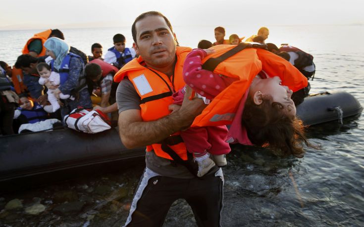 A Syrian refugee carries a child as they arrive at a beach on the Greek island of Kos after crossing a part of the Aegean sea from Turkey to Greece on a dinghy August 13, 2015. The United Nations refugee agency (UNHCR) called on Greece to take control of the "total chaos" on Mediterranean islands, where thousands of migrants have landed. About 124,000 have arrived this year by sea, many via Turkey, according to Vincent Cochetel, UNHCR director for Europe.  REUTERS/Yannis Behrakis  TPX IMAGES OF THE DAY