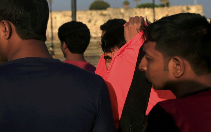 A migrant looks on as he removes his lifejacket at the port of Kos, following a rescue operation off the Greek island of Kos