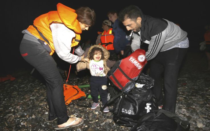 Syrian refugees dress-up their child with dry clothes moments after arriving at a beach on the Greek island of Kos after crossing a part of the Aegean sea from Turkey to Greece on a dinghy August 13, 2015. The United Nations refugee agency (UNHCR) called on Greece to take control of the "total chaos" on Mediterranean islands, where thousands of migrants have landed. About 124,000 have arrived this year by sea, many via Turkey, according to Vincent Cochetel, UNHCR director for Europe. REUTERS/Yannis Behrakis