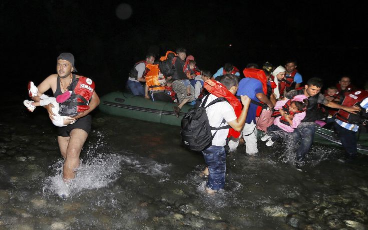 A Syrian refugee carries a child as they arrive at a beach on the Greek island of Kos after crossing a part of the Aegean sea from Turkey to Greece on a dinghy August 13, 2015. The United Nations refugee agency (UNHCR) called on Greece to take control of the "total chaos" on Mediterranean islands, where thousands of migrants have landed. About 124,000 have arrived this year by sea, many via Turkey, according to Vincent Cochetel, UNHCR director for Europe. REUTERS/Yannis Behrakis