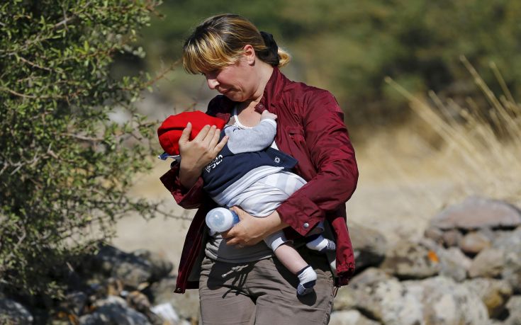 A Syrian migrant woman walks to the shore with her baby to board a dinghy bound for the Greek island of Lesbos, in the Turkish coastal town of Behramkale