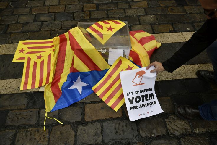A pro independences supporter holds up a sign calling for the vote close to a mock ballot boxes covered with ''esteleda'' or Catalan pro independence flags in support of the Catalonia's secession referendum, in Pamplona, northern Spain, Sunday, Oct. 1, 2017. Catalonia's regional government is holding a referendum Sunday on the possibility of breaking away from Spain, despite Spain's Constitutional Court ordering the vote to be suspended and prompting a police crackdown. (AP Photo/Alvaro Barrientos)