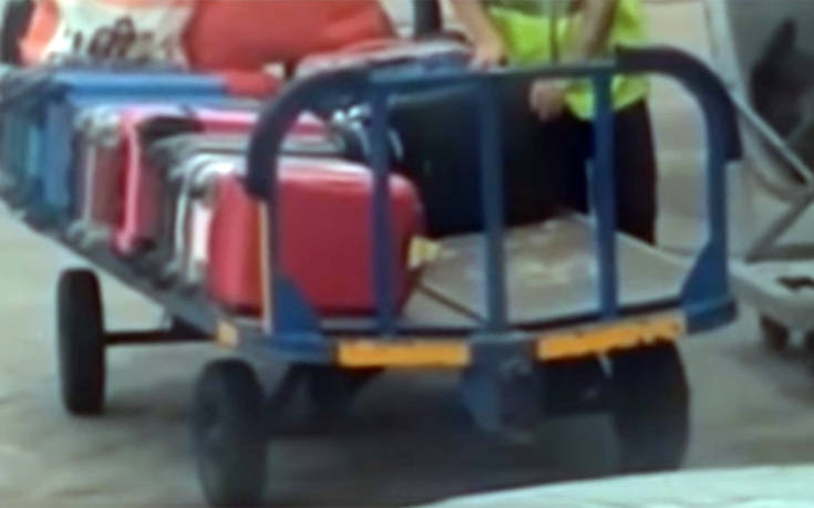 Υπάλληλος αεροδρομίου βάζει χέρι σε βαλίτσα επιβάτη