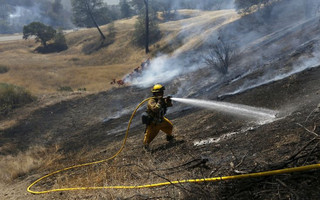 A firefighter mops up a hot spot along Highway 20 during the Rocky Fire near Lower Lake, California August 3, 2015. The blaze, which has scorched about 60,000 acres (24,281 hectares) east of Lower Lake, a town about 110 miles (180 km) north of San Francisco, was the fiercest of 20 large fires being battled by 9,000 firefighters across the state, officials said. REUTERS/Stephen Lam