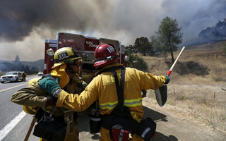 Two firefighter from Long Beach, California prepare to battle a spot fire along Highway 20 during the Rocky Fire near Lower Lake, California August 3, 2015. The blaze, which has scorched about 60,000 acres (24,281 hectares) east of Lower Lake, a town about 110 miles (180 km) north of San Francisco, was the fiercest of 20 large fires being battled by 9,000 firefighters across the state, officials said. REUTERS/Stephen Lam