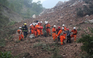 Rescue workers remove people from the site after a landslide hit a mining factory in Shanyang county