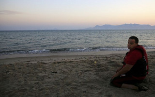 A Syrian refugee prays after landing a beach of the Greek island of Kos