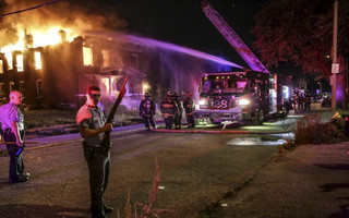 Firefighters attempt to put out a fire at an abandoned building with the protection of St. Louis City Police in St. Louis