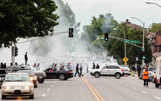 Smoke rises as police attempt to disperse protesters on Page  Ave. after a shooting incident in St. Louis