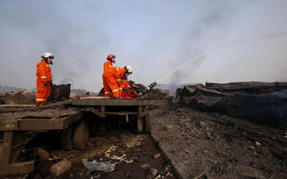 Firefighters wearing gas masks try to put out a fire at the site of Wednesday night's explosions in Binhai new district of Tianjin