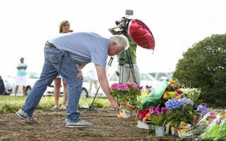 A man places flowers at a memorial outside of the offices for WDBJ7 in Roanoke