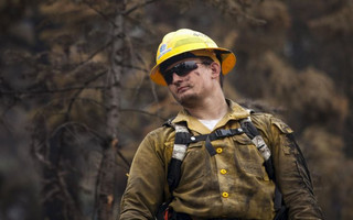 A firefighter pauses while extinguishing hot spots in areas burned by the Chelan Complex fire in Chelan, Washington