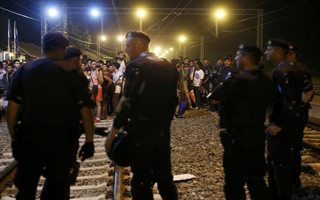 Croatian police stand guard in front of migrants at the train station in Tovarnik