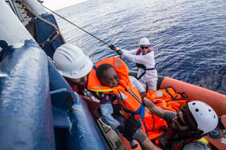 7 month old Nana, is handed from an inflatable boat to a member of MSF's sea rescue team from teh Dignity I vessel 02 September 2015. Nana was born in Libya while his parents were enroute from gambia to the coast enroute to Europe. In all 1658 people were rescued by the MOAS and MSF teams on board of the Dignity I, Bourbon Argos and MY Phoenix on this the busiest day of rescues in the Mediterranean for MSF since its operations began.