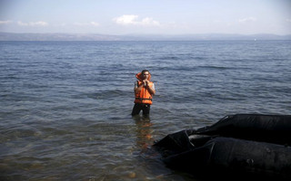A Syrian refugee washes in the sea moments after arriving on a dinghy on the island of Lesbos