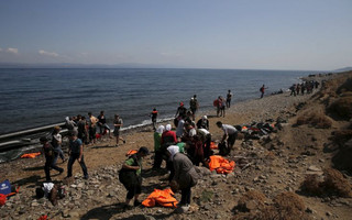 Syrian refugees and Afghan migrants are seen on a beach moments after arriving on dinghies on the island of Lesbos