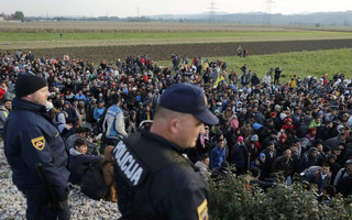 Slovenian police officers watch as migrants walk from Dobova towards a transit camp in Brezice, Slovenia October 21, 2015.   REUTERS/Antonio Bronic