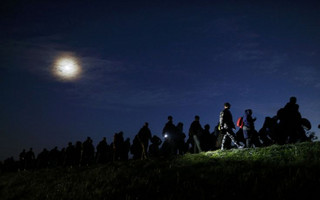 Migrants are silhouetted against the sky as they walk from Dobova towards a transit camp in Brezice, Slovenia October 21, 2015.   REUTERS/Antonio Bronic