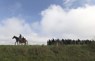 A mounted policeman leads a group of migrants near Dobova, Slovenia October 20, 2015. Slovenia's parliament is expected to approve changes to its laws later on Tuesday to enable the army to help police guard the border, as thousands of migrants flooded into the country from Croatia after Hungary sealed off its border. REUTERS/Srdjan Zivulovic TPX IMAGES OF THE DAY