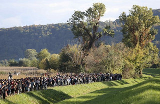 Migrants walk as mounted policemen watch them near Brezice, Slovenia October 20, 2015. Slovenia's interior ministry raised the possibility on Tuesday of setting up physical barriers along its southeastern border if the numbers of migrants increased. REUTERS/Srdjan Zivulovic