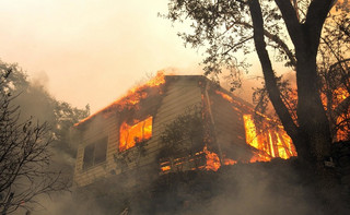 Flames from a massive wildfire consume a home on the Silverado Trail, Monday, Oct. 9, 2017, east of Napa, Calif. (AP Photo/Rich Pedroncelli)
