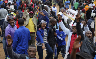 Protesters dance and sing, one holding a poster asking President Mugabe to step down, at a demonstration at Zimbabwe Grounds in Harare, Zimbabwe Saturday, Nov. 18, 2017. Opponents of President Robert Mugabe are demonstrating for the ouster of the 93-year-old leader who is virtually powerless and deserted by most of his allies. (AP Photo/Ben Curtis)