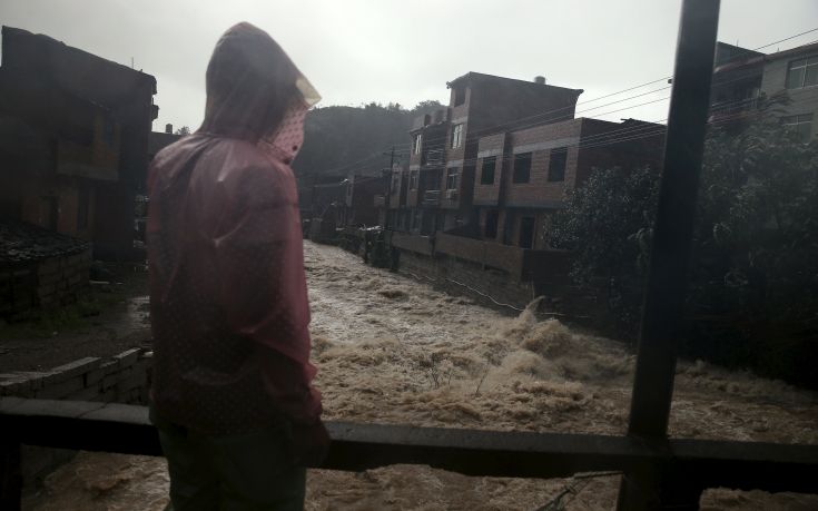 A man watches floodwaters in a heavy rain at a town hit by Typhoon Soudelor in Ningde, Fujian province, China, August 9, 2015. Typhoon Soudelor landed on the coast of Putian City in southeast China's Fujian Province late Saturday after lashing Taiwan, bringing strong winds and downpours and causing power outages in the province and neighboring Zhejiang, state media CCTV reported. REUTERS/Stringer CHINA OUT. NO COMMERCIAL OR EDITORIAL SALES IN CHINA
