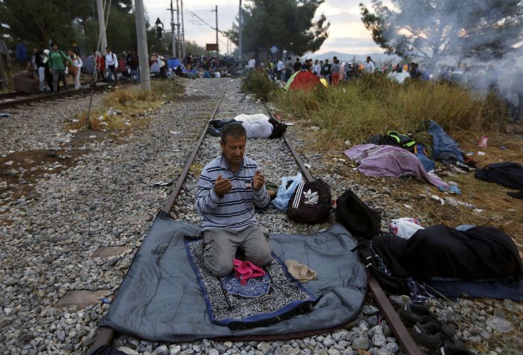 A Syrian refugee prays on a rail track at the Greek-Macedonian border, near the village of Idomeni, August 22, 2015. Crowds of migrants and refugees were building on Greece's border with Macedonia on Saturday after a cold, wet night spent in the open, their entry slowly rationed by Macedonian police and soldiers.    REUTERS/Yannis Behrakis TPX IMAGES OF THE DAY
