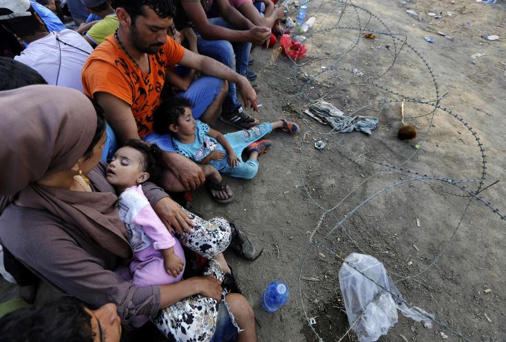 Syrian refugees sit in front of a barbed-wire at the Greek-Macedonian border, near the village of Idomeni, August 21, 2015. Macedonian police fired tear gas and stun grenades to drive migrants and refugees back from its southern border from Greece on Friday but crowds continued to build up at a new bottleneck in an increasingly desperate flight to western Europe. At least 10 people were hurt in the brief flare-up, a day after the impoverished Balkan country declared a state of emergency on its border to halt a daily influx of up to 2,000 Syrians, Afghans, Iraqis and others heading north.   REUTERS/Yannis Behrakis