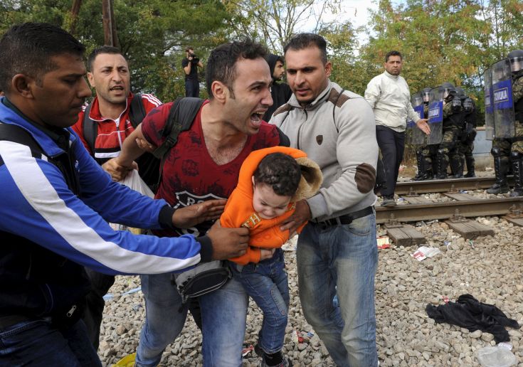 A migrant reacts as he carries a child during clashes with Macedonian police at the Greek-Macedonian border, August 21, 2015. Macedonian police drove back crowds of migrants and refugees trying to enter from Greece on Friday after a night spent stranded in no-man's land by an emergency decree effectively sealing the Macedonian frontier. A Reuters reporter said tear gas was fired and saw at least four bloodied migrants taken for treatment on the Greek side of the border.. REUTERS/Alexandros Avramidis A migrant reacts as he carries a child during clashes with Macedonian police at the Greek-Macedonian border, August 21, 2015. Macedonian police drove back crowds of migrants and refugees trying to enter from Greece on Friday after a night spent stranded in no-man's land by an emergency decree effectively sealing the Macedonian frontier. A Reuters reporter said tear gas was fired and saw at least four bloodied migrants taken for treatment on the Greek side of the border.. REUTERS/Alexandros Avramidis