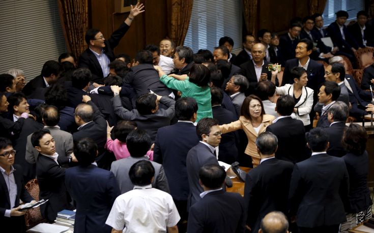 Lawmakers crowd around Yoshitada Konoike, chairman of the upper house special committee on security, during a vote at an upper house special committee session on security-related legislation at the parliament in Tokyo