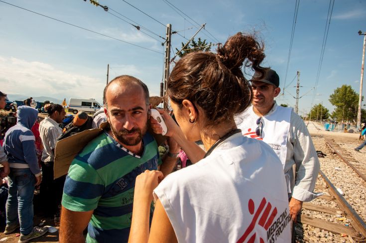 MSF Doctor, Stavroula Kostaki, checks the temperature of a patient in a queue. He is feeling ill but he does not want to leave his group because he is about to cross the border to Macedonia at Idomeni. MSF Doctor, Stavroula Kostaki, checks the temperature of a patient in a queue. He is feeling ill but he does not want to leave his group because he is about to cross the border to Macedonia at Idomeni.