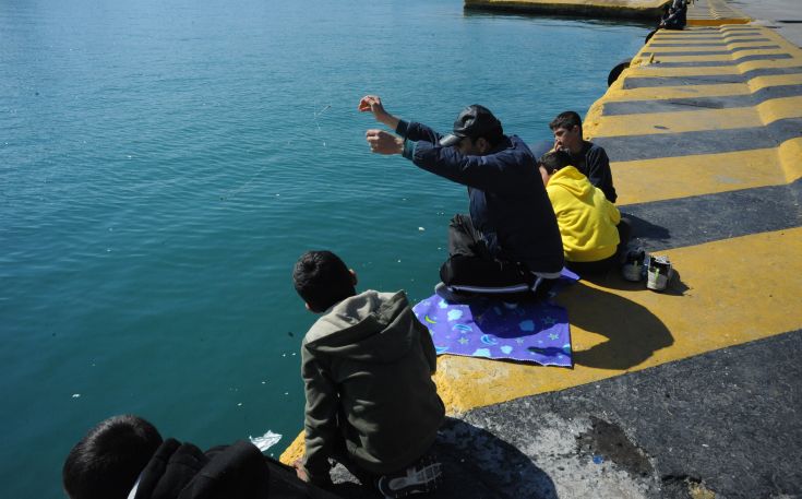 Πρόσφυγας ψαρεύει στο λιμάνι του Πειραιά
