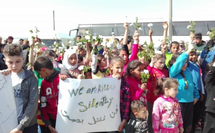 Παιδιά πρόσφυγες με λευκά λουλούδια και πανό στην Ειδομένη