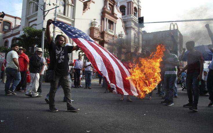 An opposition supporter burns a flag of the United States, who recognized disputed election results handing victory in November's presidential election to incumbent Juan Orlando Hernandez, during a march and rally led by opposition leader Salvador Nasralla in San Pedro Sula, Honduras, Saturday, Jan. 6, 2018. Following an election marred by irregularities, Hernandez was declared the victor and will be inaugurated on Jan. 27. Nasralla reaffirmed his claim on the presidency and said he would not stop calling for protests and civil disobedience until Hernandez agrees to step down. (AP Photo/Fernando Antonio)