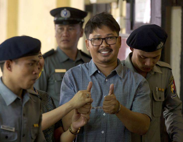 Reuters journalist Wa Lone, center, thumbs up as he is escorted by police upon arrival at their trial Monday, May 21, 2018, Yangon, Myanmar. The two reporters, Wa Lone and Kyaw Soe Oo, have been detained since Dec. 12 on charges of violating the colonial-era Official Secrets Act. (AP Photo/Thein Zaw)