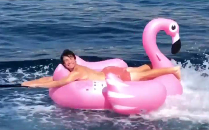 Σέρφινγκ πάνω σε ροζ φουσκωτό φλαμίνγκο