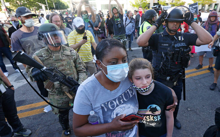 Η φρίκη στις ΗΠΑ μέσα από ένα φωτογραφικό κλικ: Αστυνομικός σημαδεύει εξ’ επαφής κοριτσάκι στους ώμους του πατέρα του