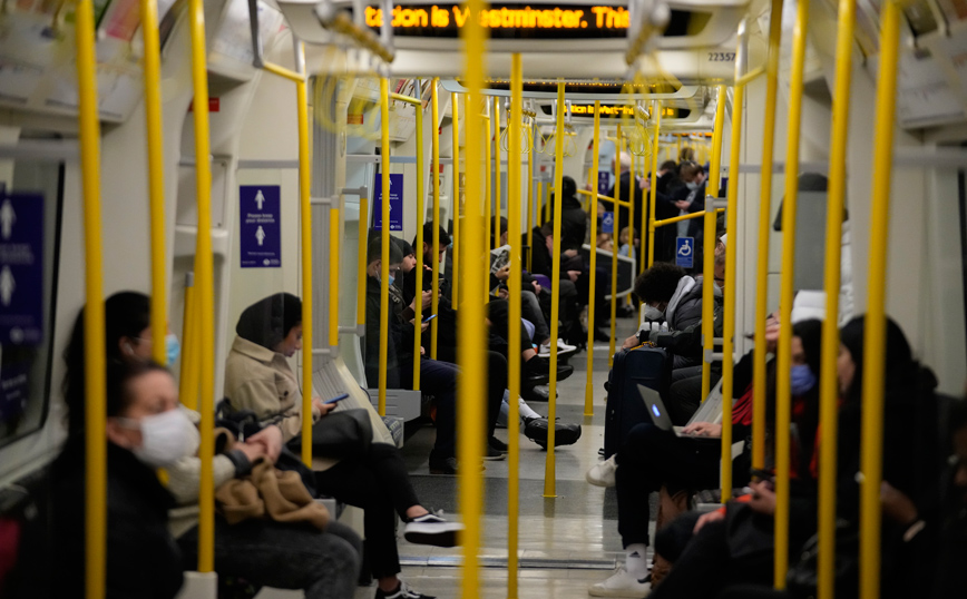 Γυναίκα με μάσκα και με μια βαλίτσα στο χέρι περπατά στο Λονδίνο ανάμεσα από περιστέρια Γυναίκα με μάσκα και με μια βαλίτσα στο χέρι περπατά στο Λονδίνο ανάμεσα από περιστέρια