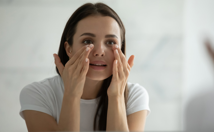 Γυναίκα εφαρμόζει καλλυντικά στο πρόσωπό της Γυναίκα εφαρμόζει καλλυντικά στο πρόσωπό της