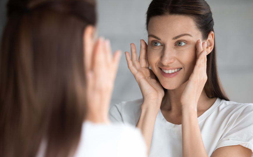 Γυναίκα περιποιείται το πρόσωπό της Γυναίκα περιποιείται το πρόσωπό της