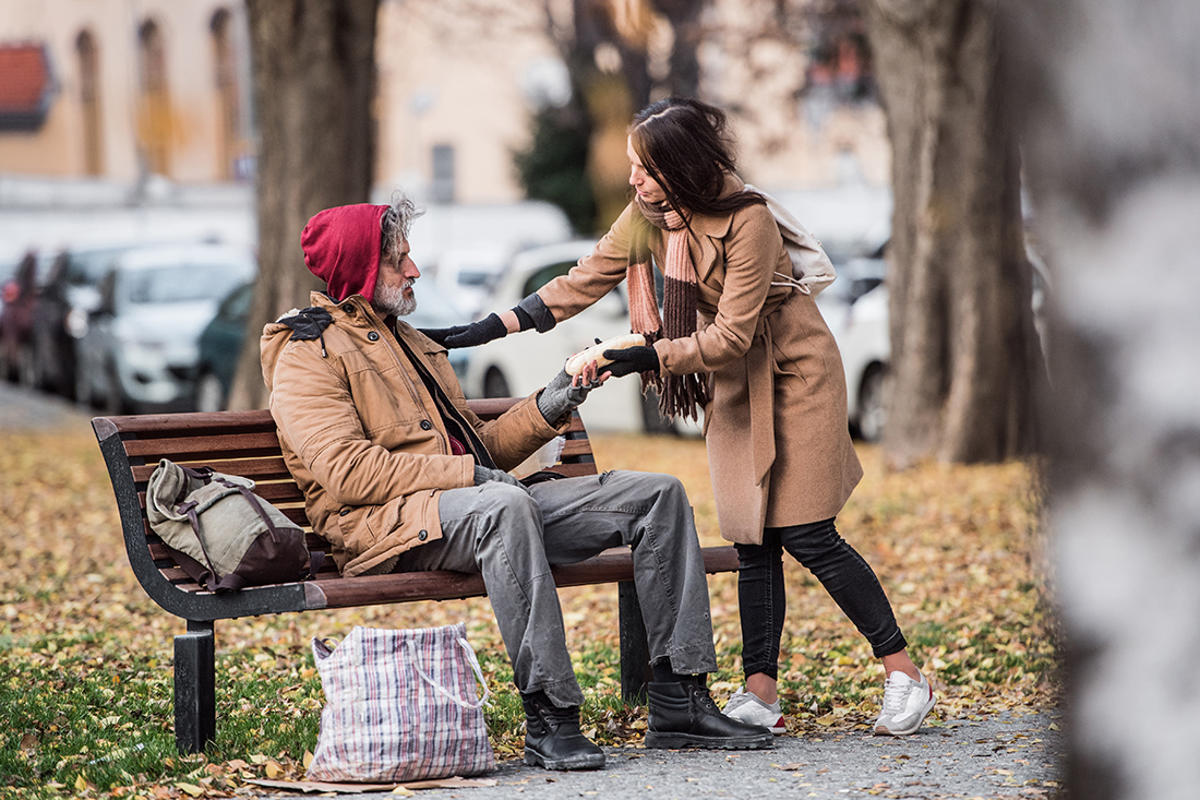 Γυναίκα βοηθά έναν άστεγο Γυναίκα βοηθά έναν άστεγο