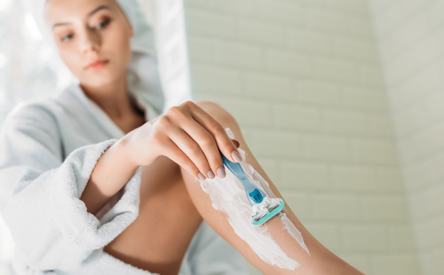 Γυναίκα ξυρίζει τα πόδια της με ξυραφάκι Γυναίκα ξυρίζει τα πόδια της με ξυραφάκι