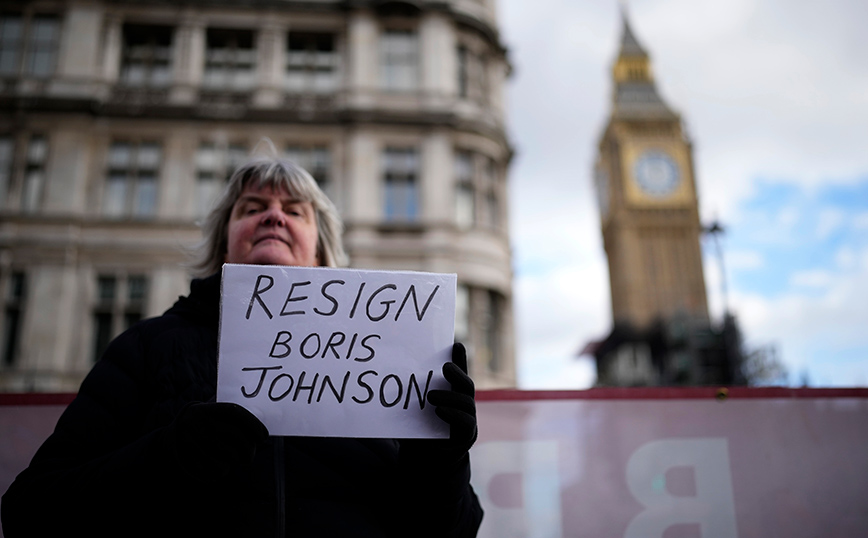 Γυναίκα κρατά χαρτί και ζητά από τον Τζόνσον να παραιτηθεί Γυναίκα κρατά χαρτί και ζητά από τον Τζόνσον να παραιτηθεί